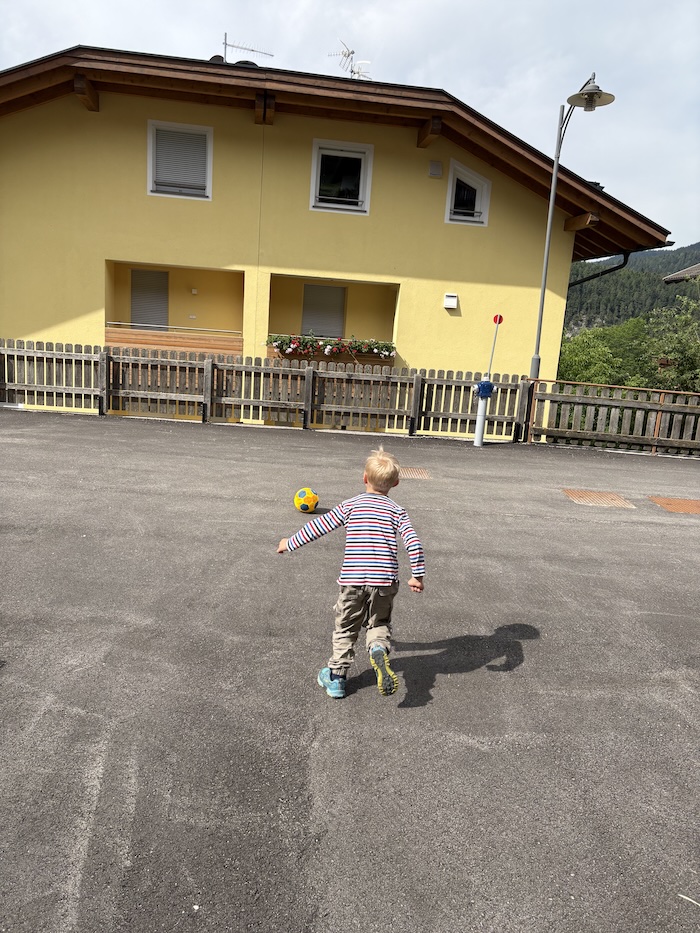 Opa und Enkel spielen gemeinsam Fußball am Ende einer ruhigen Sackgasse
