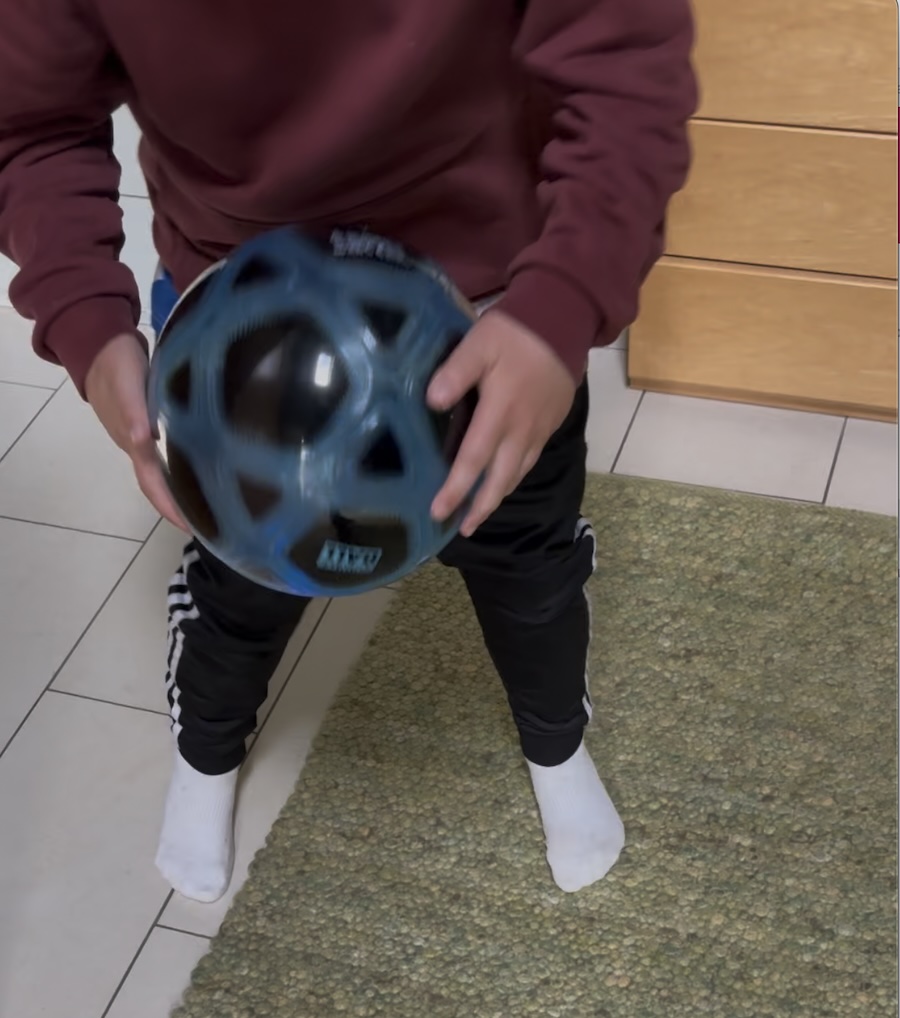 Enkel hält einen blauen Counter Ball (Zählball) in den Händen