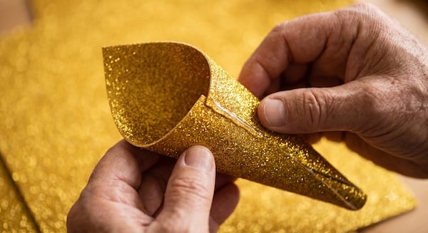 Aus goldenem Glitzerpapier wird ein spitzer Kegel als Einhorn-Horn geformt