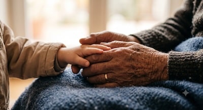 Hand eines Großvaters hält tröstend die Hand des Enkelkindes – schwere Zeiten gemeinsam tragen