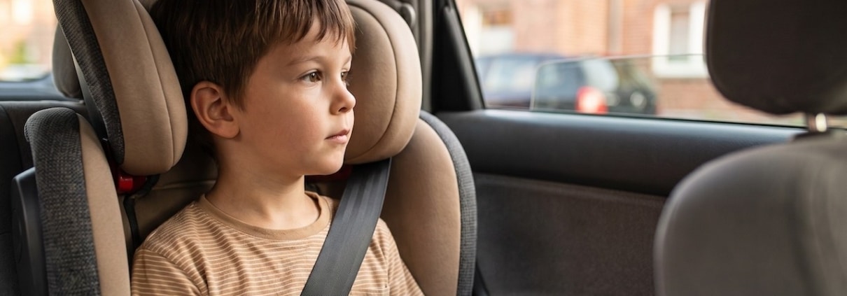 Kind in einem vorwärtsgerichteten Kindersitz mit Rückenlehne auf der Rückbank, angeschnallt mit dem Fahrzeuggurt
