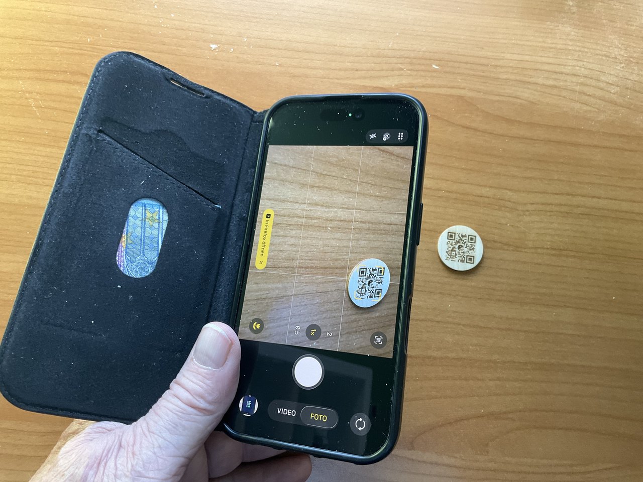Ein iPhone scannt mit der Kamera den QR-Code auf einem Holzplättchen
