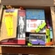 Offener Karton mit Holzpuzzle, Büchern, Quizspiel und Bauklötzen — ein gepacktes Paket für das Enkelkind in Südtirol